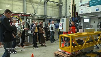Ein Mitarbeiter des DSC erläutert einer Besuchergruppe eine Forschungsanlage.